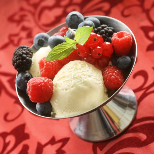 Vanilla Ice Cream Dessert with Mixed Berries on a Red Background