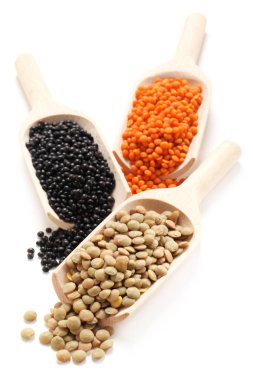 Tahta kürekler üzerindeki üç çeşit mercimek beyaza izole edilmiş.