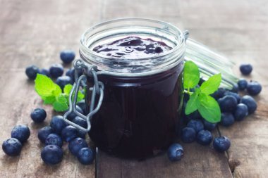 Tahta bir arka planda bir kavanoz yaban mersini reçeli