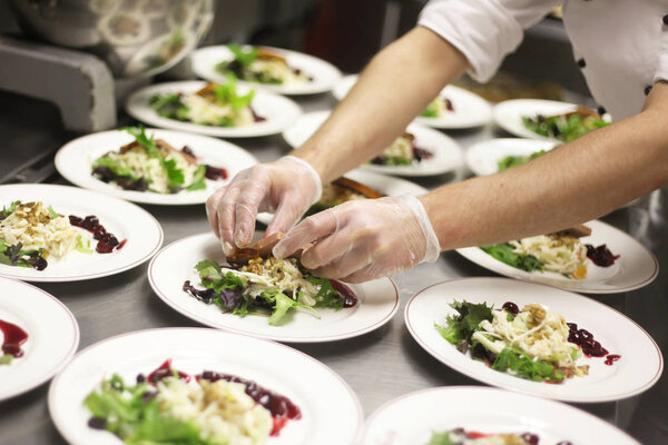 chef decorating plates of salad in restaurant