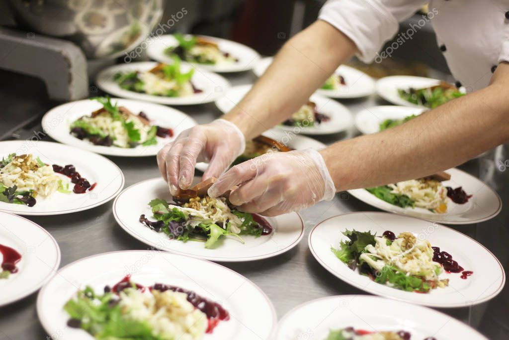 chef decorating plates of salad in restaurant