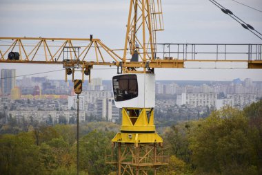 İnşaat vinci. Gökyüzüne karşı inşaat vinci. Doğayla çevrili kentsel binaların arka planında inşaat vinci.