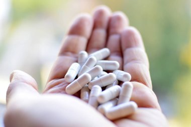 Doktorun avucundaki tabletler ve kapsüller ve beyaz arka plandaki yakın plan fotoğrafçılığı. Tedavi için eldeki ilaç