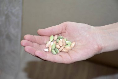 Beslenme takviyeleri. Sağlık desteği ve tedavi. Beyaz duvar arkasında el ele tutuşan spirulina hapları. Sabah vitamin besin hapı. Biyolojik olarak aktif katkı maddeleri