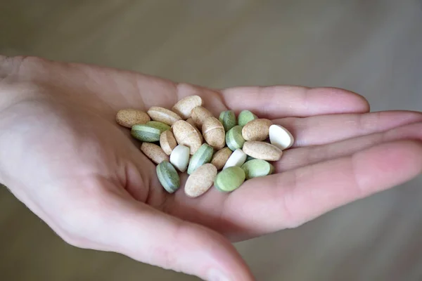 Dietary supplements. Health support and treatment. Hand holding spirulina pills on white wall background. Morning vitamin nutrient pill. Biologically active additives