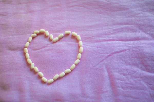 Κάψουλες Σχήμα Καρδιάς Στο Ροζ Ύφασμα Φόντο Ημέρα Του Αγίου — Φωτογραφία Αρχείου