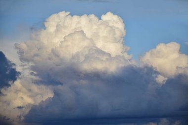 Kabarık bulutlar mavi gökyüzü. Akşam güneşiyle aydınlanan koyu bulutlar mavi gökyüzü parıldıyor..