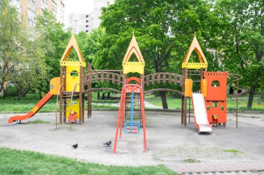 Büyük bir şehrin içindeki bir meydanda renkli bir oyun alanı. Boş çocuk parkı karantina günleri için kapatıldı.