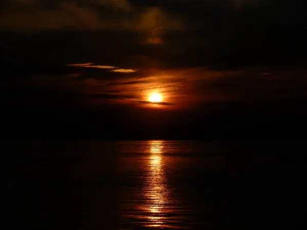 Драматичний літній захід сонця ввечері з відображенням сонця на воді — стокове фото
