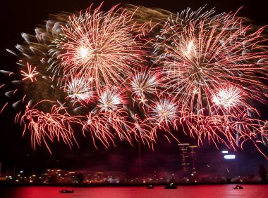 Muhteşem bir yangın gösterisi. Heyecan verici kırmızı ve gül renginde havai fişekler geceleyin patlıyor..