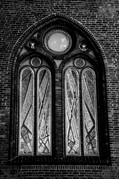 Antikes Bogenfenster an einer Ziegelwand in monochromer Farbe. Ein Detail aus der Nähe einer Kirche. — Stockfoto