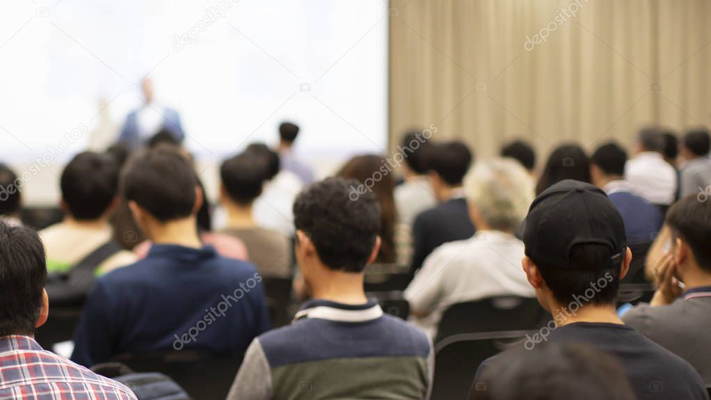 Corporate seminar for tech entrepreneurs in auditorium. Audience participants in development workshop. Executive manager giving speech at symposium. Business training at university lecture hall.