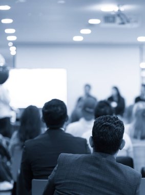 Kurumsal konferansta seminer sunucusu konuşma yapıyor. Konuşmacı iş izleyicilerine ders veriyor. Şirket eğitimi etkinliği sırasında salonda tartışma yürüten yönetici. 