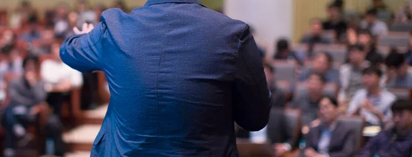 Business man making a presentation at office. Business executive delivering a presentation to his colleagues during meeting or in-house workshop. Rear view. Business and entrepreneurship.