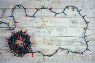 Christmas background with colorful lights and free text space. Garland lights frame on a wooden background. 
