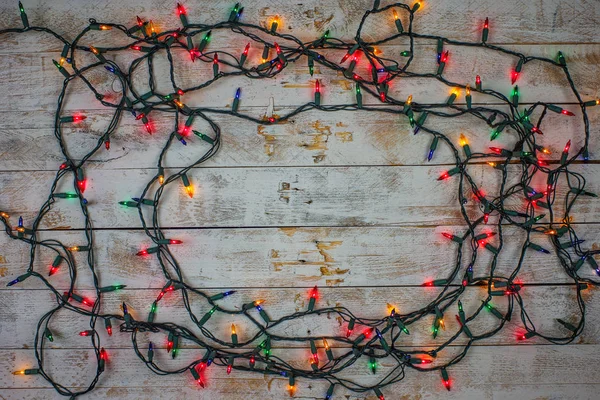 Christmas lights over white painted planks for background. Christmas light decorations on wood texture. — Stock Photo, Image