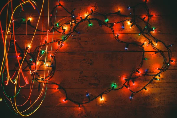 Colorful Christmas garland warm lights. Multicolored light lines. Wooden background. — Stock Photo, Image