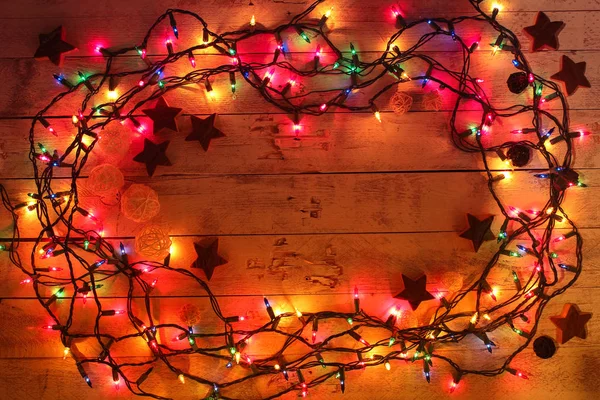 Glowing colorful Christmas lights on wooden background. Christmas wooden decor. Garland. — Stock Photo, Image