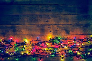 Colorful Christmas garland warm lights. Multicolored lights. Wooden background. 