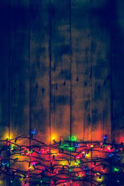 Colorful Christmas garland warm lights. Multicolored lights. Wooden background. — Stock Photo, Image