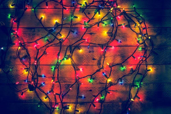 Glowing colorful Christmas lights on a wooden background. Christmas decor. Garland. — Stock Photo, Image