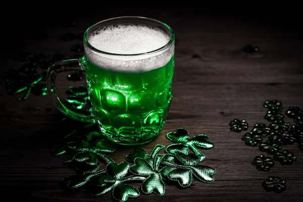 St. Patrick\'s Day. Green Beer pint on wooden table, decorated with shamrock leaves. Glass of Green beer close-up. Selective focus. Blurred background. Bokeh.