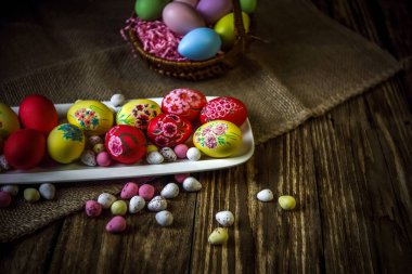 Ahşap bir arka planda paskalya kompozisyonu. Paskalya yumurtalarını elle boyamak. Dini bayramlar, aile gelenekleri. Seçici odaklanma. Yatay oryantasyon. Boşluğu kopyala.
