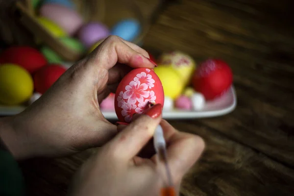 Female hands painting eggs with floral patterns acrylic. Decorating egg. Preparation for Easter. Close-up. Horizontal orientation. Copy space.
