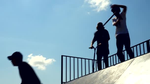 Epische silhouet van skater rijden op kick scooter. - Dag. Blauwe lucht. Langzame beweging — Stockvideo