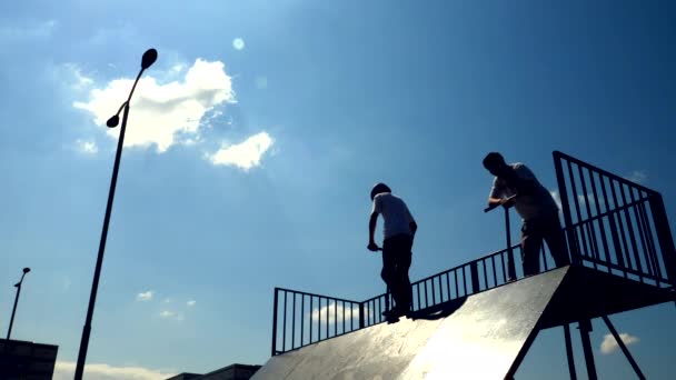 Silhouette di pattinatore sul calcio scooter saltare a parco pattinaggio urbano. Rallentatore . — Video Stock