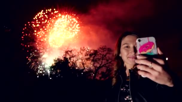 Slow Motion: Portret van een meisje gebruik smart phone, beeld van vuurwerk achtergrond — Stockvideo