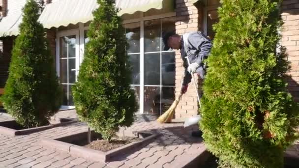 ほうきで屋外に掃く黄疸の男性。カフェの近くの土地を掃除する男 — ストック動画