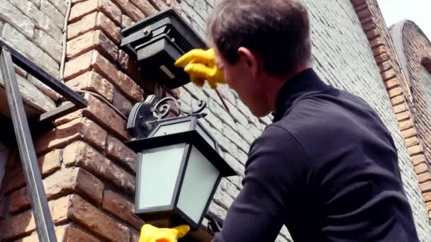 Elektricien man installeren klassieke lamp in outdoor lantaarn in een latex handschoenen — Stockvideo