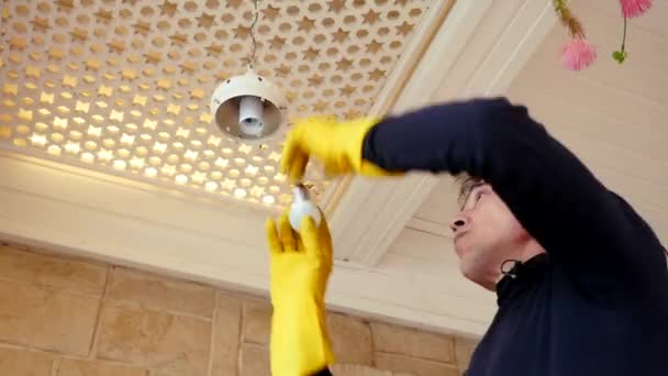 Professional electrician twisting bulb installing light in chandelier. apartment — Stock Video