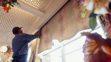 Hizmetli, Roma panjurları için perdeleri cırt cırtlı bağlayıcıyla hızlıca soyar.