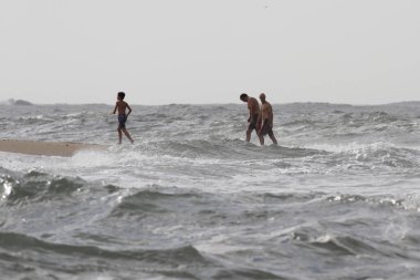 Early Autumn bathers in a rough sea beach