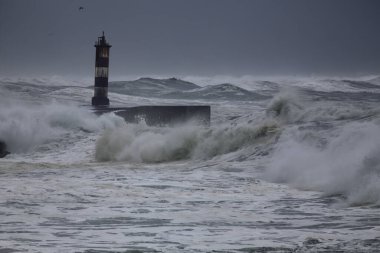 Kış dalgalı denizi. Nehir ağzı feneri ve iskele. Vila do Conde, Portekiz
