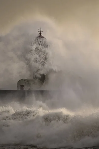 Old lighthouse at the mouth of the Douro River during storm at sea seeing water running after being hit by violent waves