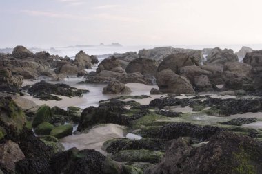Alacakaranlıkta Rocky plajı. Uzun pozlama. Kuzey Portekiz kayalık kıyıları.