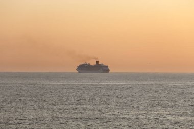Portekiz sahilini geçen yolcu gemisi güneybatı turuncu gün batımına ya da alacakaranlığa doğru ilerliyor.