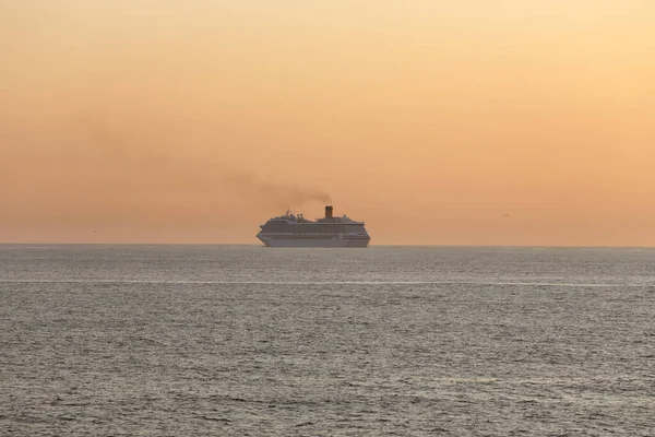 Portekiz sahilini geçen yolcu gemisi güneybatı turuncu gün batımına ya da alacakaranlığa doğru ilerliyor.