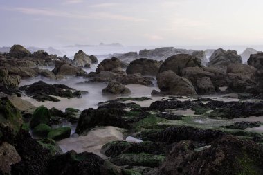 Alacakaranlıkta Rocky plajı. Uzun pozlama. Kuzey Portekiz kayalık kıyıları.