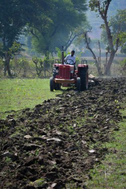 Tikamgarh, Madhya Pradesh, Hindistan - 10 Kasım 2019: Traktörlü Hintli çiftçi harrow ekimi için arazi hazırlıyor.