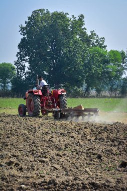 Tikamgarh, Madhya Pradesh, Hindistan - 10 Kasım 2019: Traktörlü Hintli çiftçi harrow ekimi için arazi hazırlıyor.