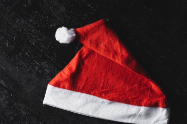 Koyu ahşap arka planda kırmızı Noel Baba şapkası. Noel / Yeni Yıl kavramı.