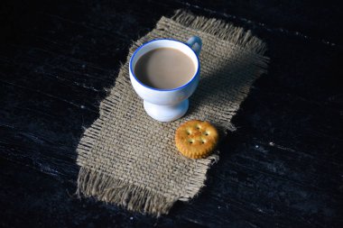 Eski ahşap arka planda bisküvili bir fincan çay.