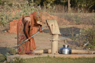 TIKAMGARH, MADHYA PRADESH, Hindistan - 24 Mart 2020: Kimliği belirsiz Hintli kadın içme suyu pompası kullanıyor.
