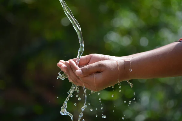 子供の手に自然を背景に水を注ぐ 水のスプラッシュと手 — ストック写真