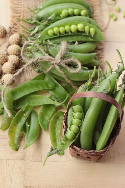 Vaina de guisantes verdes frescos sobre fondo de madera — Foto de Stock