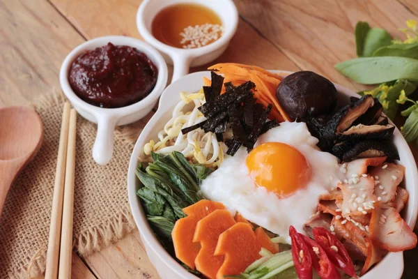 Bibimbap comida coreana es delicioso sobre fondo de madera —  Fotos de Stock
